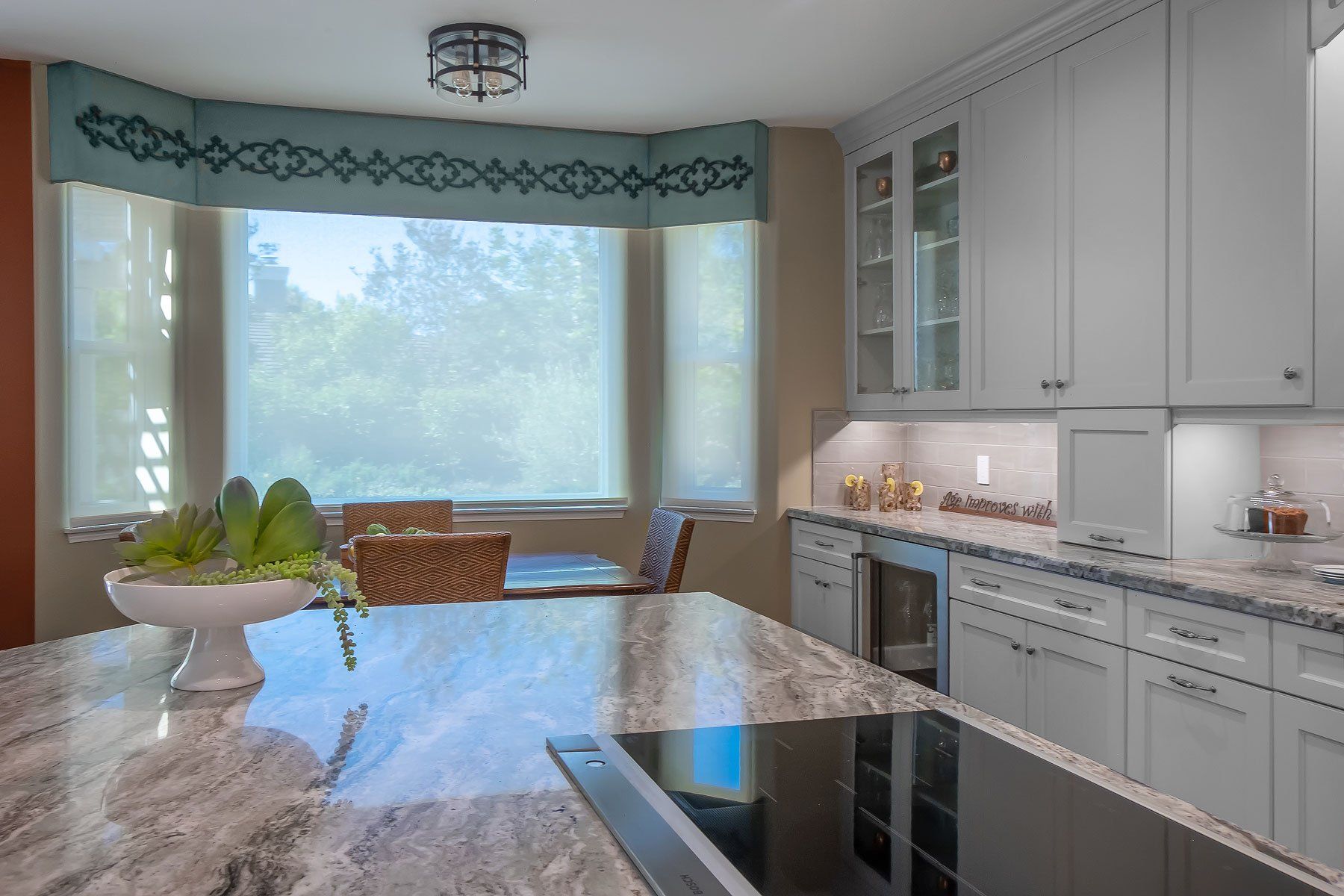 Bright modern kitchen with white cabinets, granite island, and large bay window