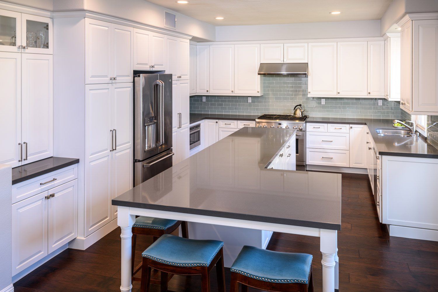 Bright modern white kitchen with stainless steel appliances and a large gray island with stools