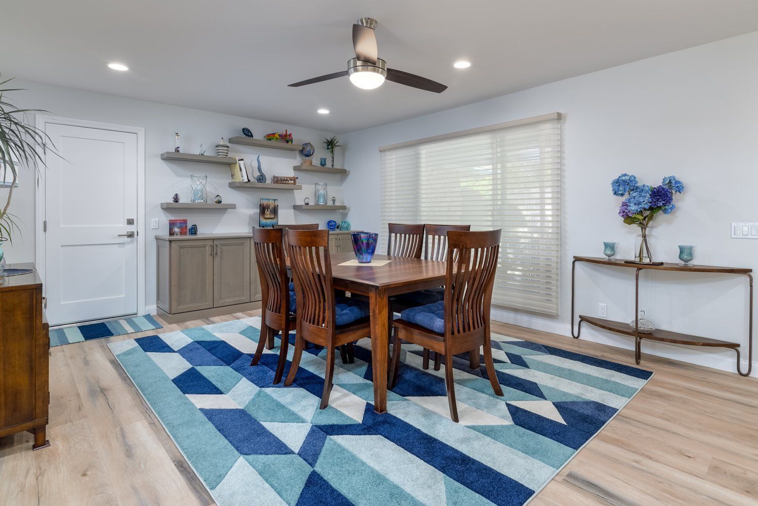 Dining room with wooden table, blue geometric rug, and sideboard in a bright, modern home