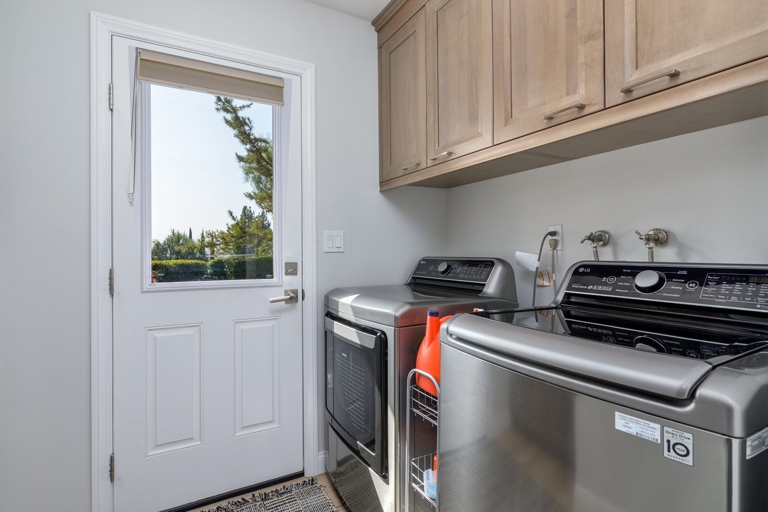 Laundry room with washer and dryer beside a white door with a window.