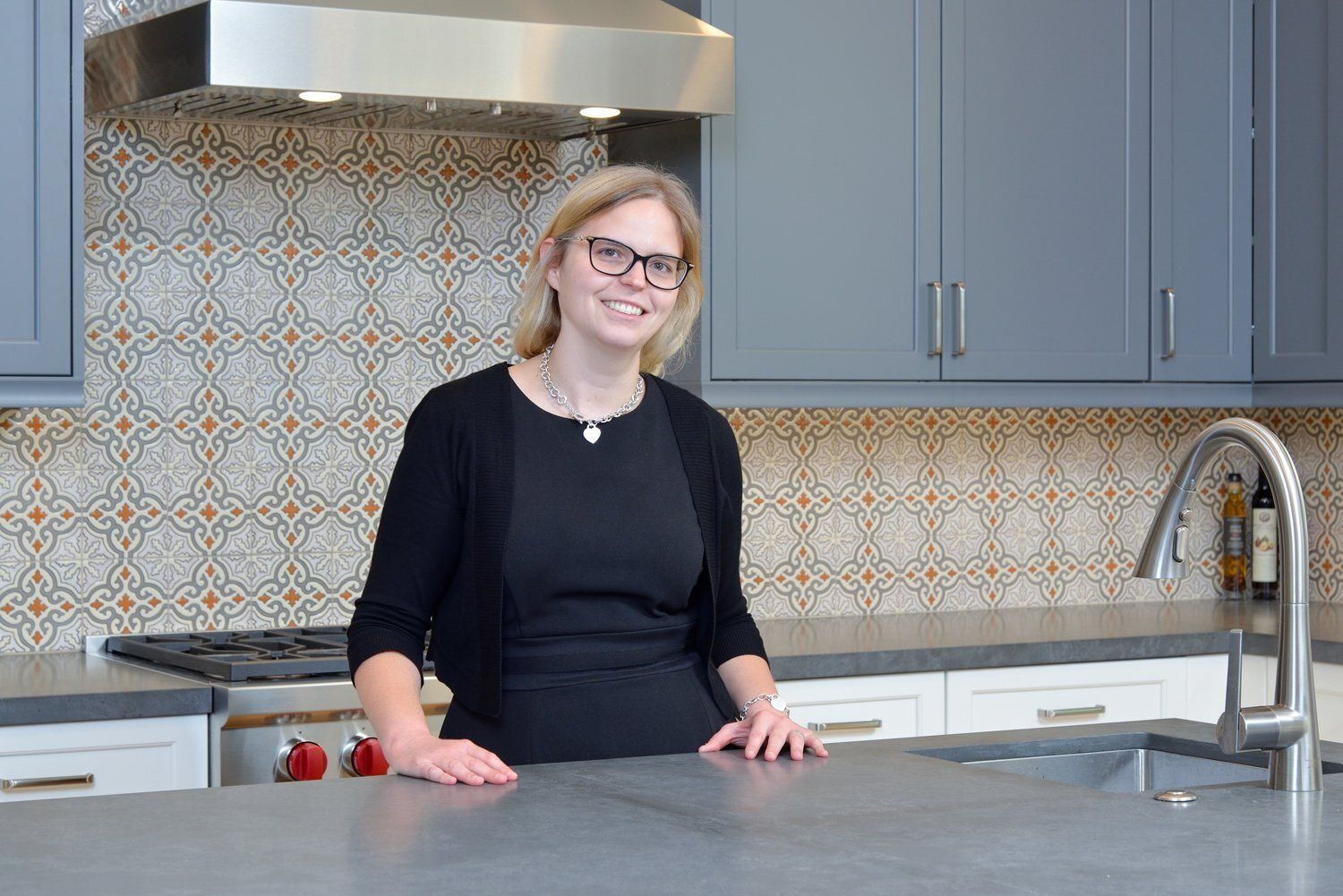 Woman standing in a modern kitchen behind a gray island counter, smiling