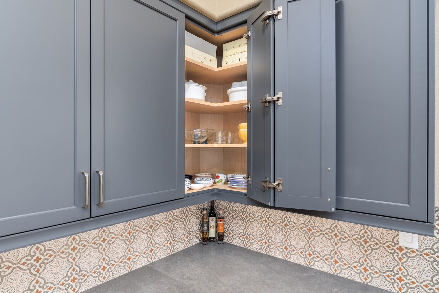 Open corner kitchen cabinets with shelves and a gray countertop beneath