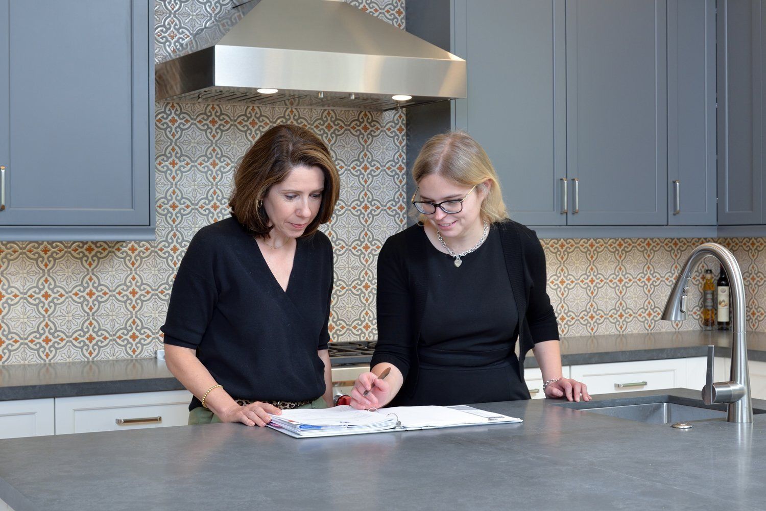 Two women reviewing papers together in a kitchen by the counter