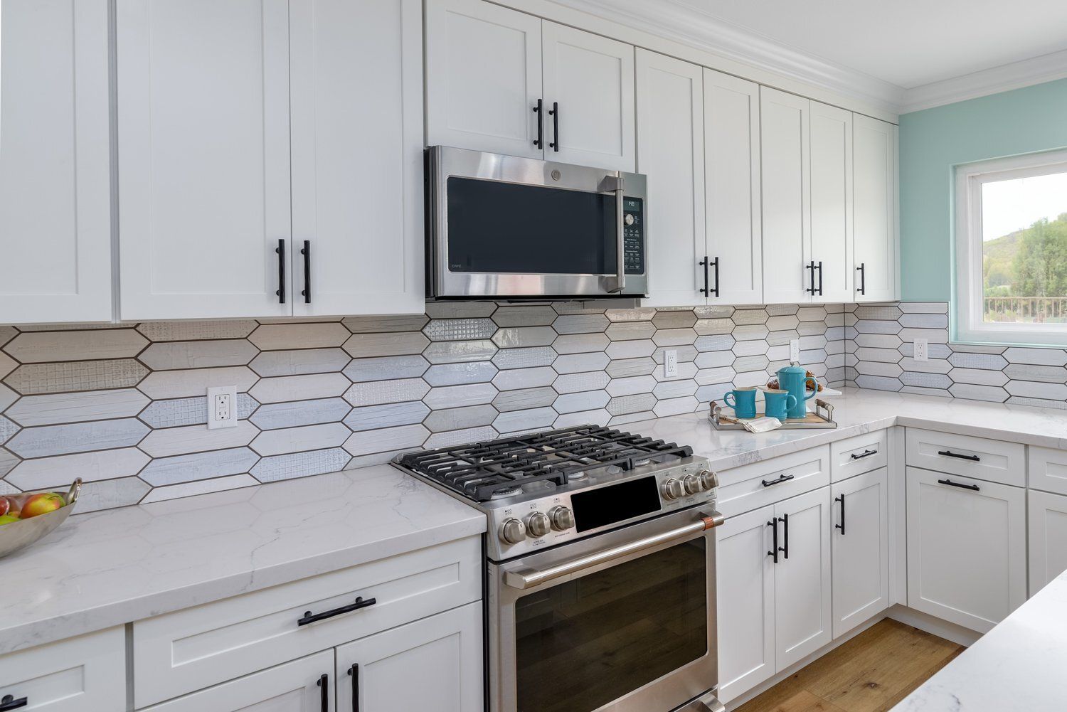 Bright white modern kitchen with stainless steel appliances and white hexagon tile backsplash