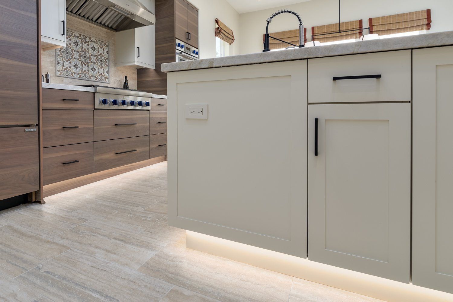 Modern kitchen with white island cabinets, light wood flooring, and stainless steel appliances in the background