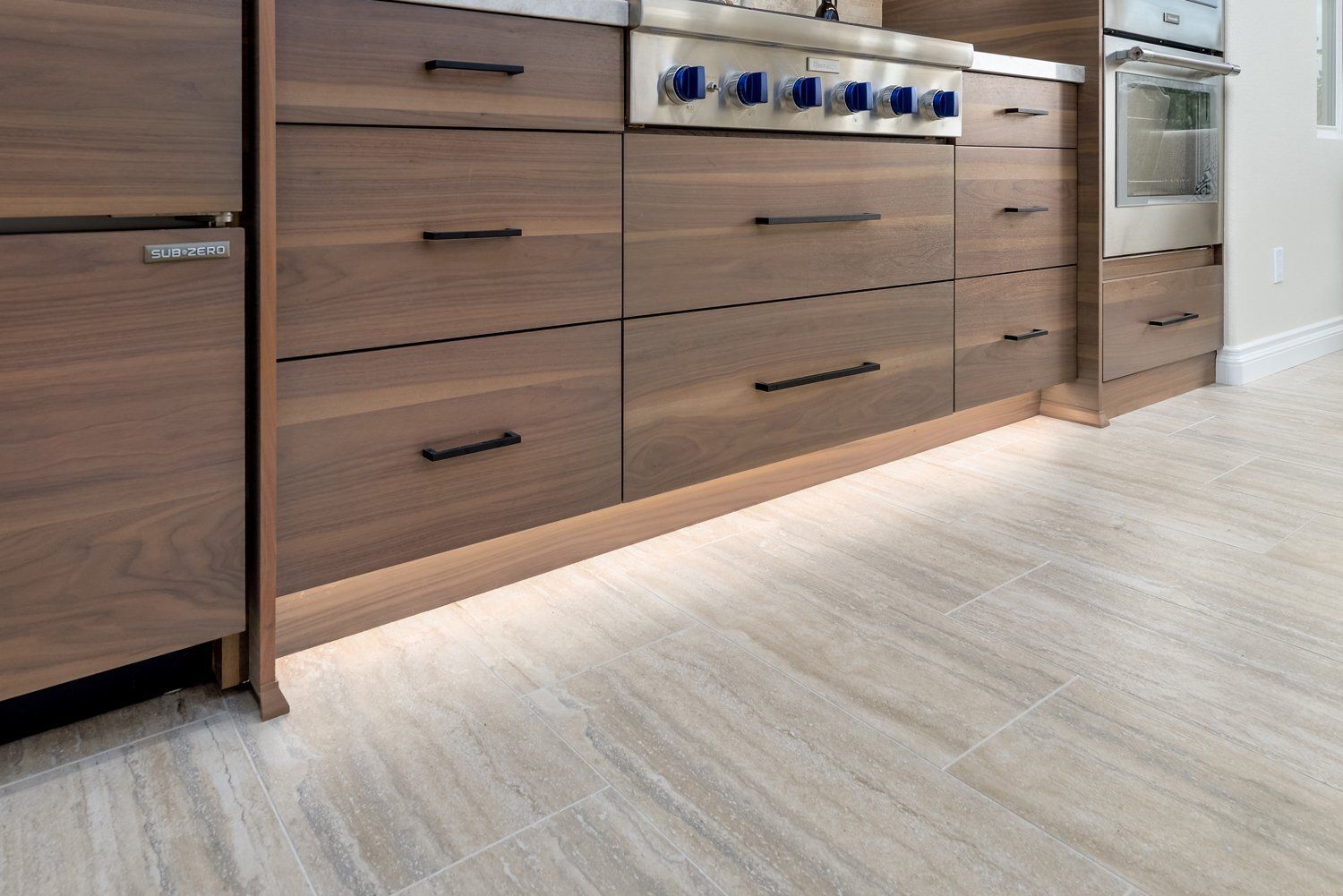 Modern kitchen with wooden cabinets, white countertop, and built-in appliances on a light floor