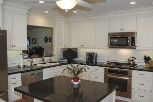 Bright modern kitchen with white cabinets, stainless steel appliances, and a dark island centerpiece