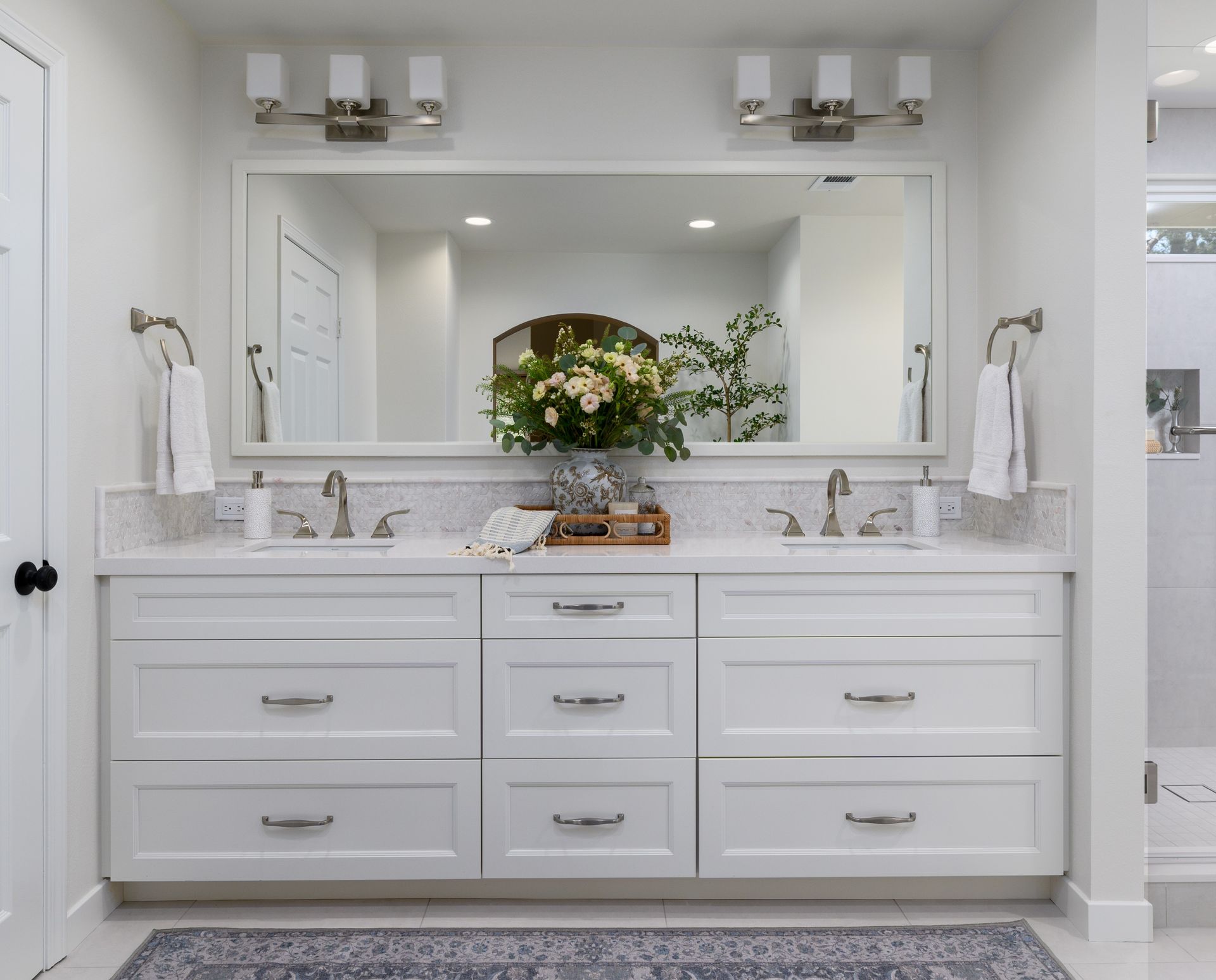 Bright modern kitchen with wood beams, white cabinets, and a large island with flowers.
