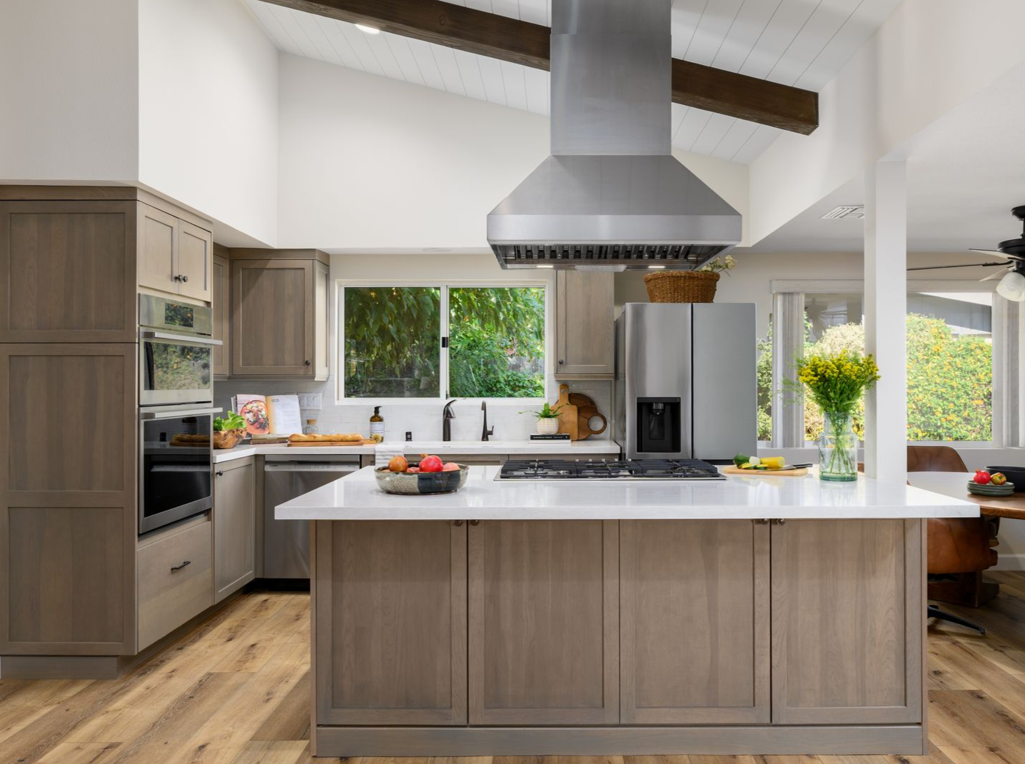 Modern kitchen with wood island, white countertops, stainless appliances, and large windows