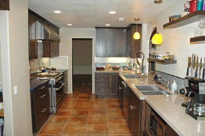 Modern kitchen with brown cabinets, tile floor, and hanging yellow pendant lights