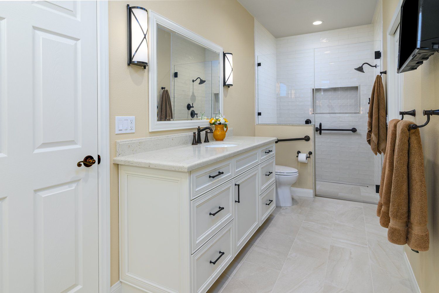 Bright modern bathroom with double vanity, mirror, shower, and beige towels