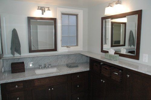 Bathroom vanity with dark wood cabinets, double sinks, mirrors, and wall sconces.