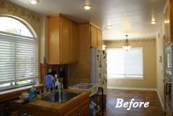 Before: narrow kitchen with wood cabinets, sink by window, and hallway leading to a bright dining area.