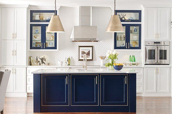 Bright white kitchen with navy blue island, pendant lights, and stainless steel appliances