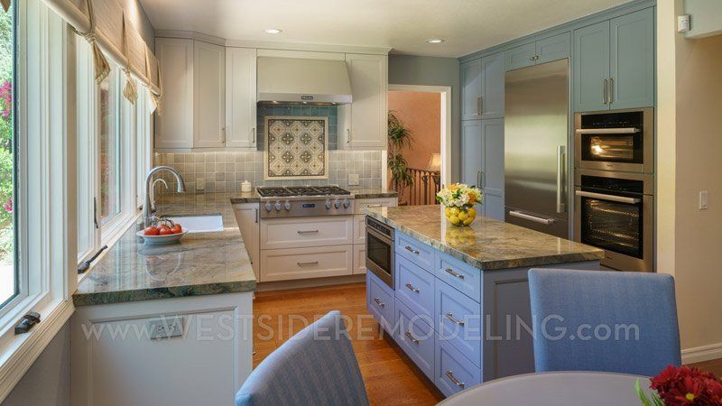 Bright modern kitchen with island, stainless appliances, wood floors, and large windows