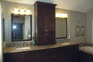 Bathroom vanity with double mirrors, granite countertop, and dark wood cabinets.