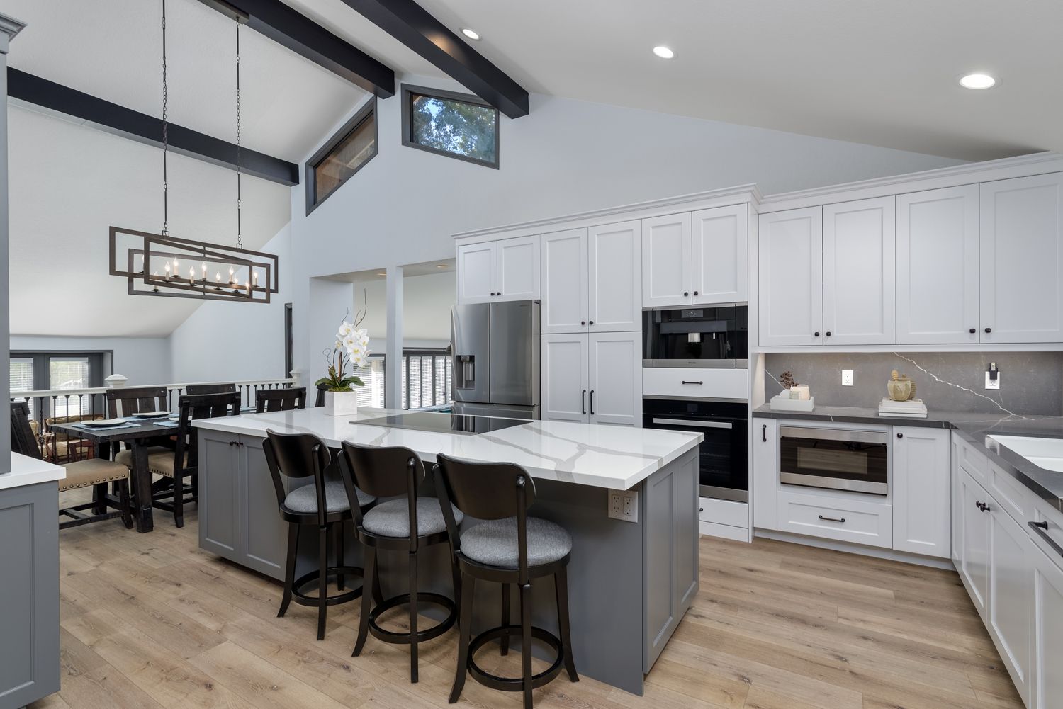 Bright modern kitchen with white cabinets, gray island, and barstools in an open-plan home