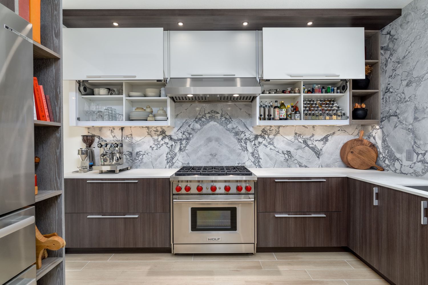 Modern kitchen with gray cabinetry, marble backsplash, stainless stove, and open shelves