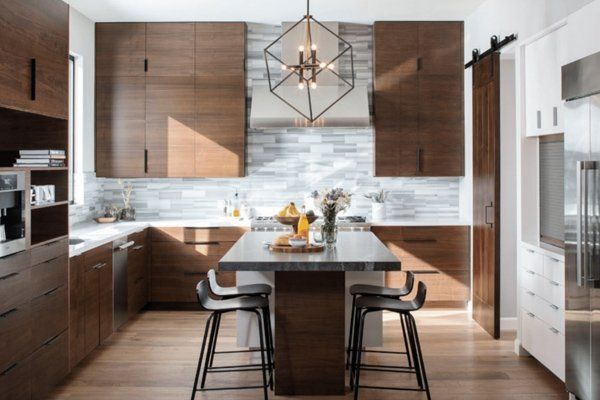 Modern kitchen with wood cabinets, marble island, bar stools, and geometric pendant light
