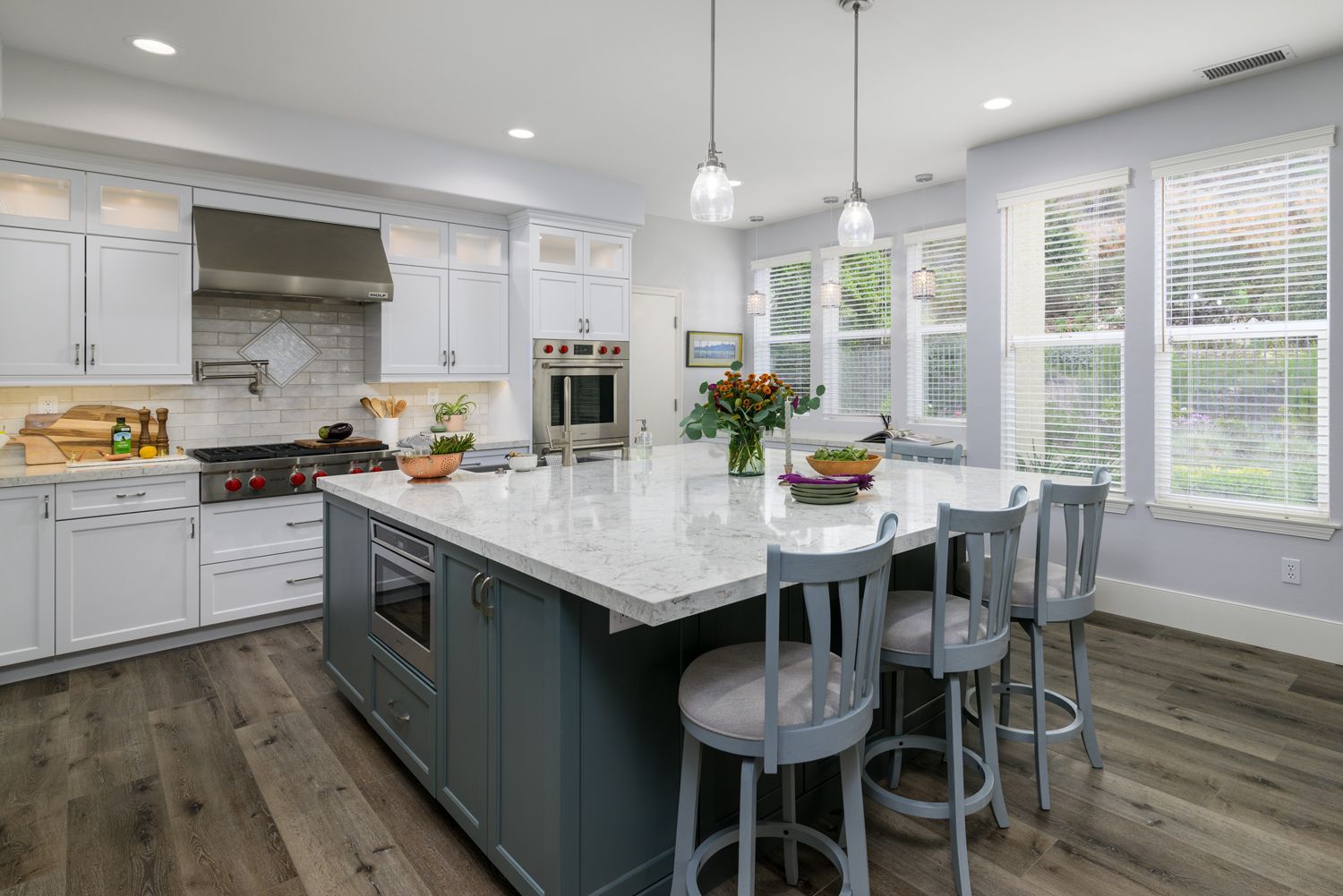 Bright modern kitchen with white cabinets, gray island, and large windows