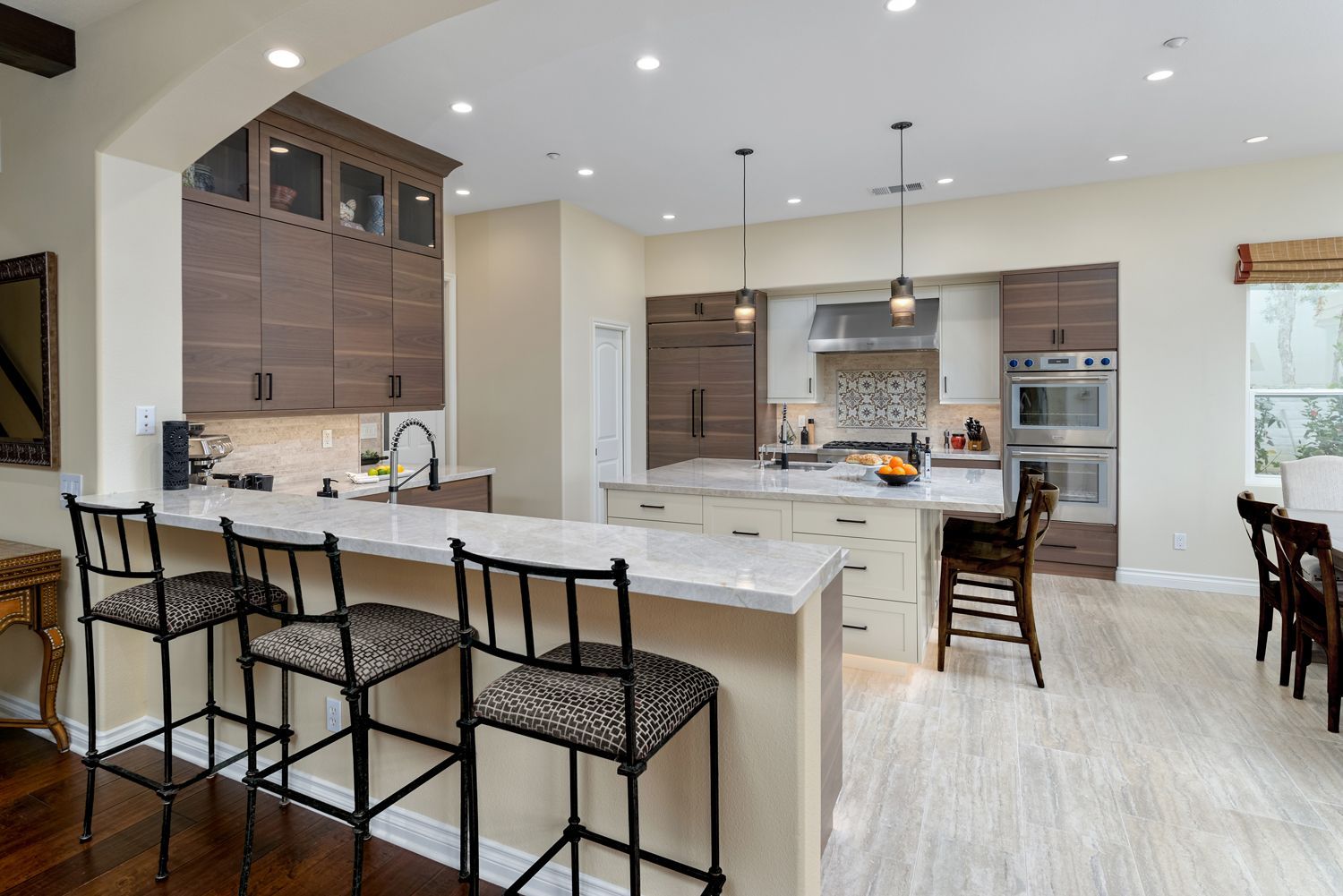 Bright modern kitchen with large white island, bar stools, and wood cabinets
