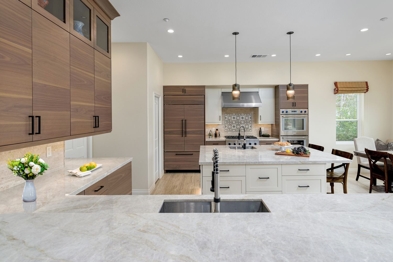 Modern kitchen with wood cabinets, marble island, stainless appliances, and bright open dining area