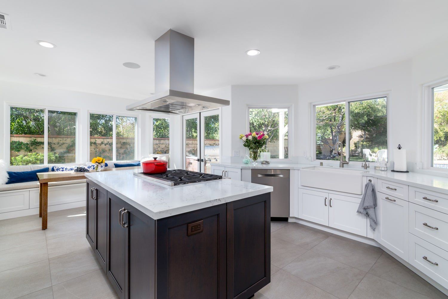 Bright modern kitchen with white cabinets, dark island, and large windows looking out to greenery