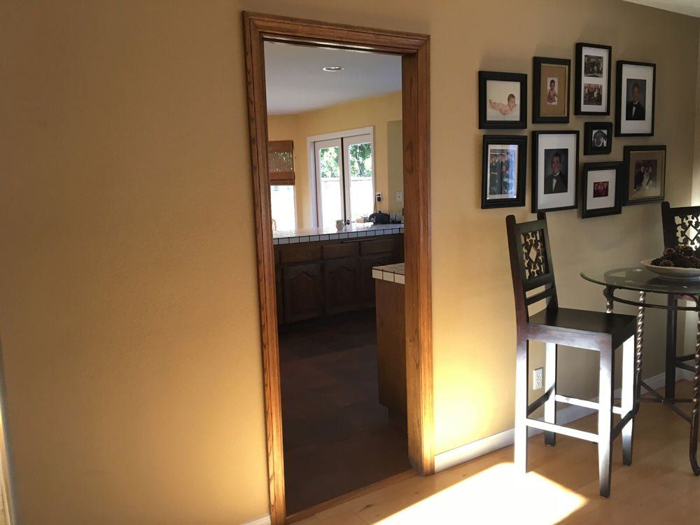 Dining room with warm wall light, doorway to kitchen, and framed photos on the wall