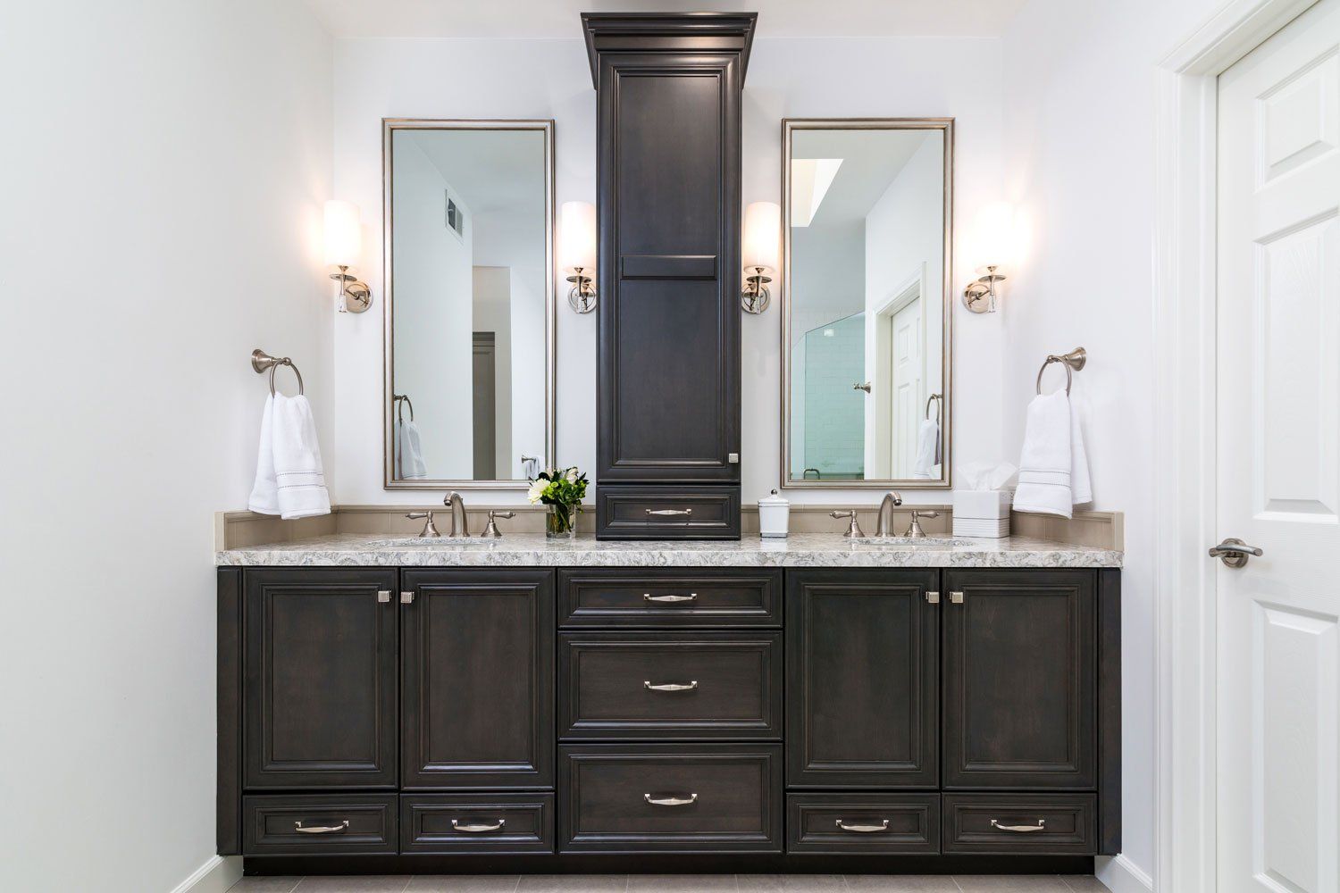 Modern bathroom vanity with dark cabinets, three mirrors, and white walls and countertops
