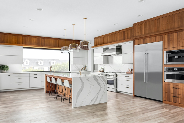 Modern kitchen with wood cabinets, stainless appliances, marble island, and light wood flooring