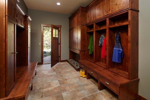 Wood-paneled mudroom with built-in benches, cubbies, and hanging coats near a doorway.