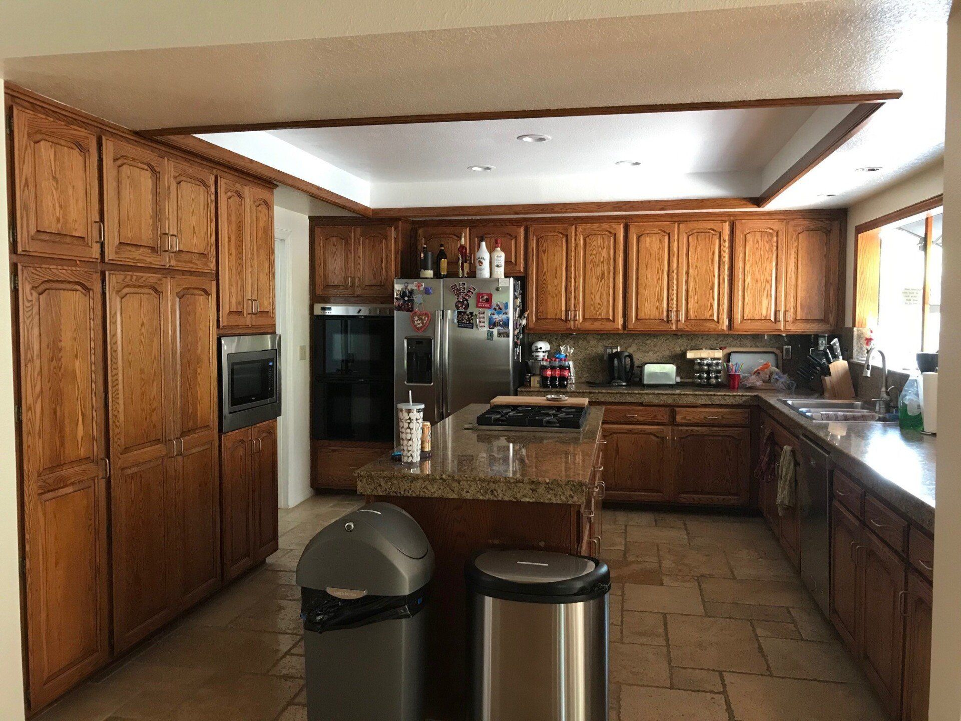 Wooden kitchen with stainless appliances, tiled floor, and a central island viewed from the doorway