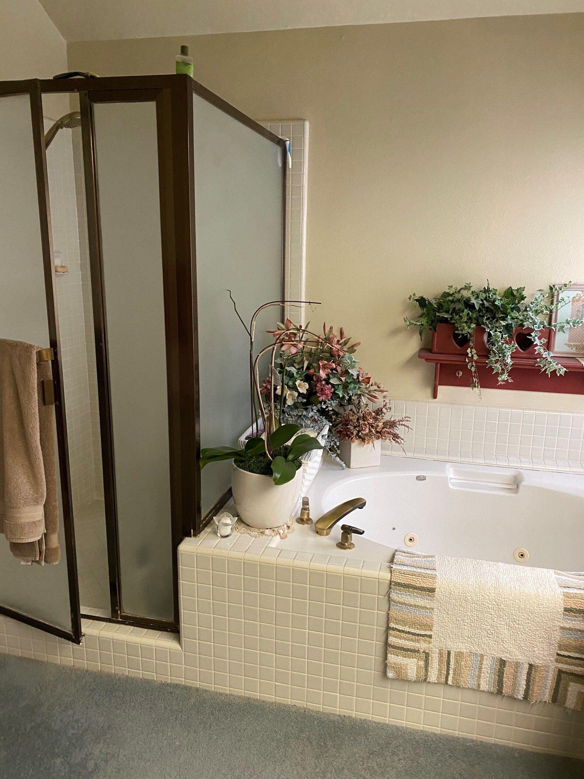 Bathroom with a large soaking tub, glass shower, and floral decor.
