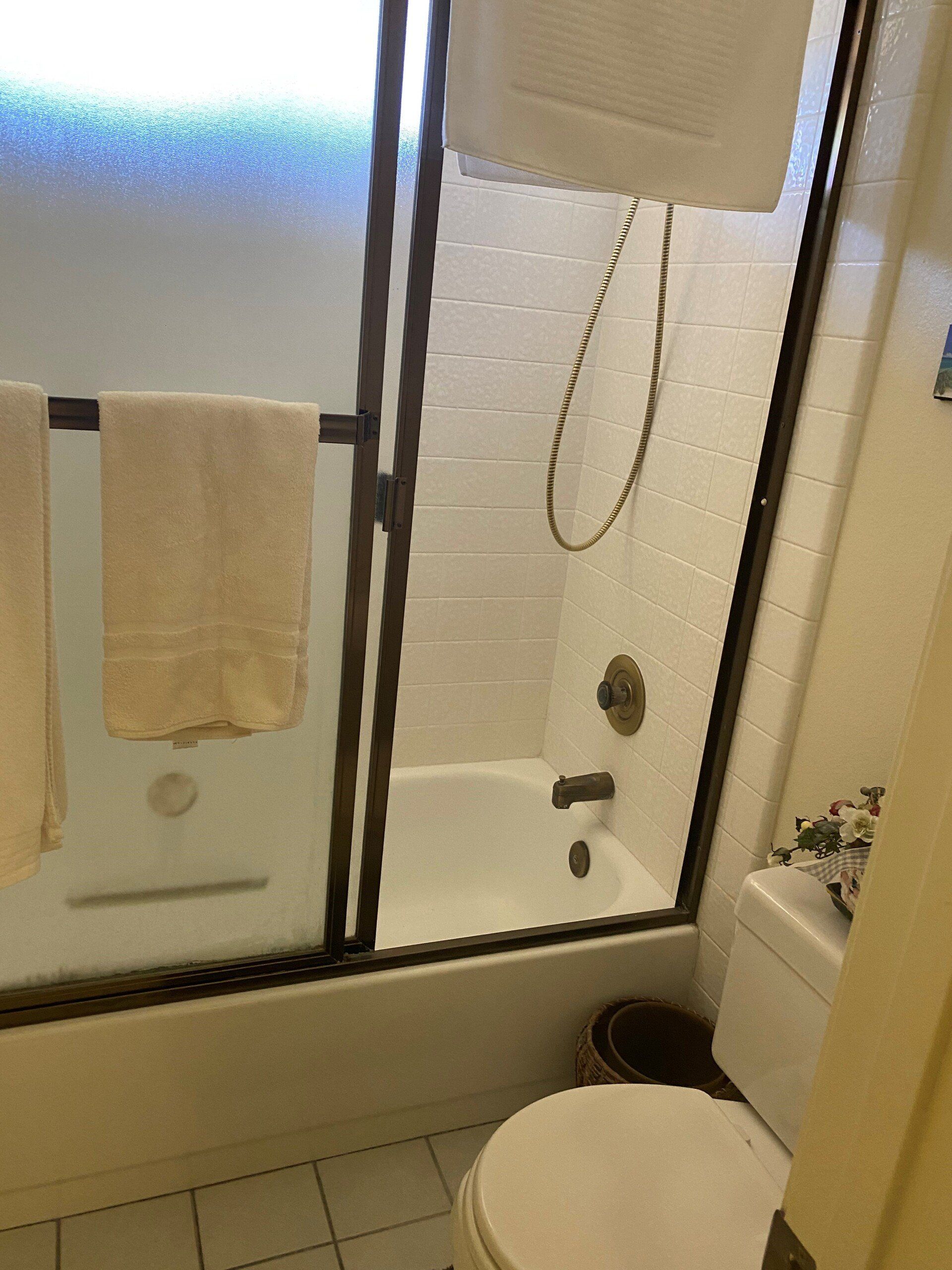 Small bathroom with a glass shower, towel rack, toilet, and sink visible.