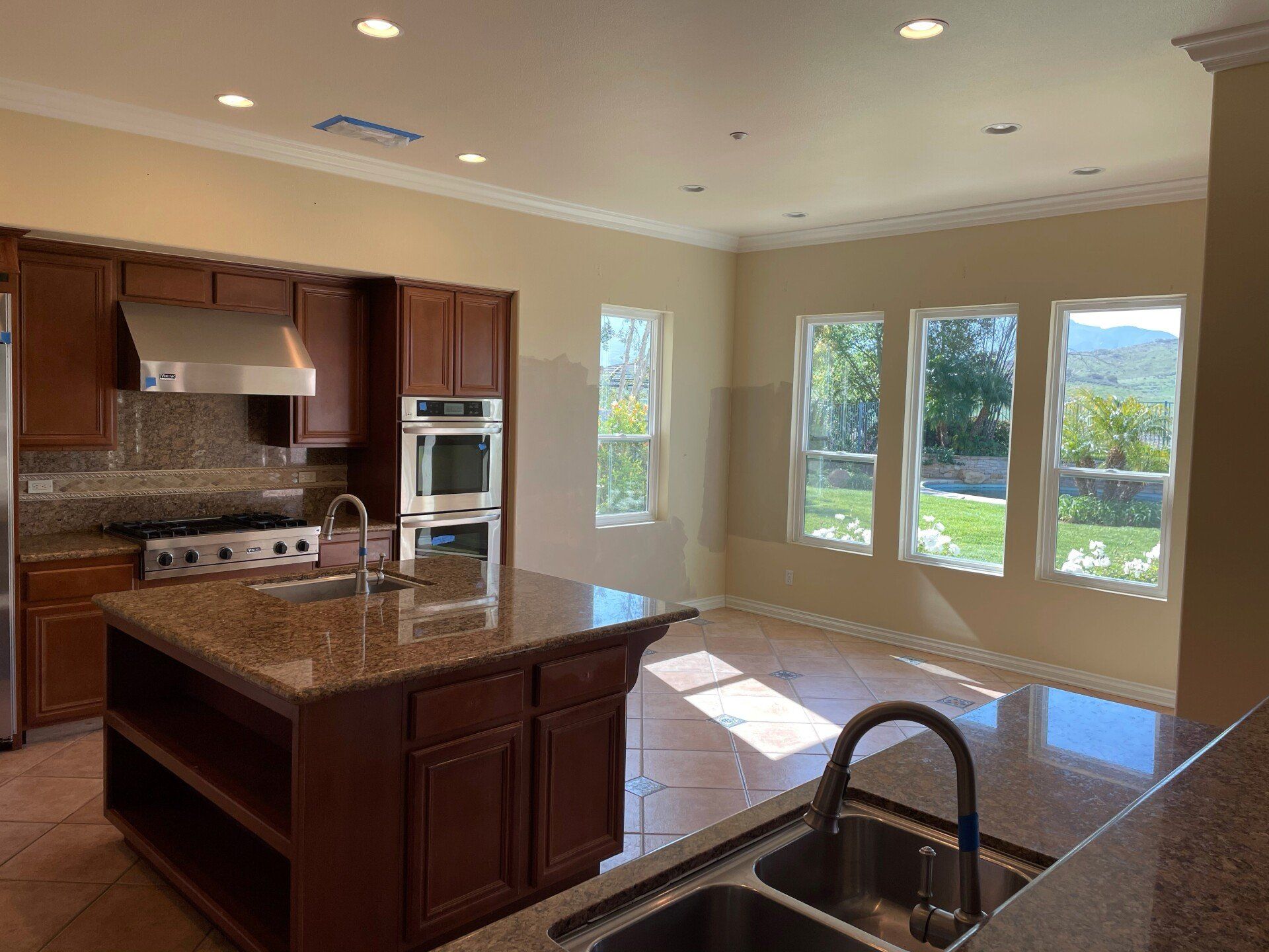Modern kitchen with dark wood cabinets, granite island, and bright windows overlooking a landscape
