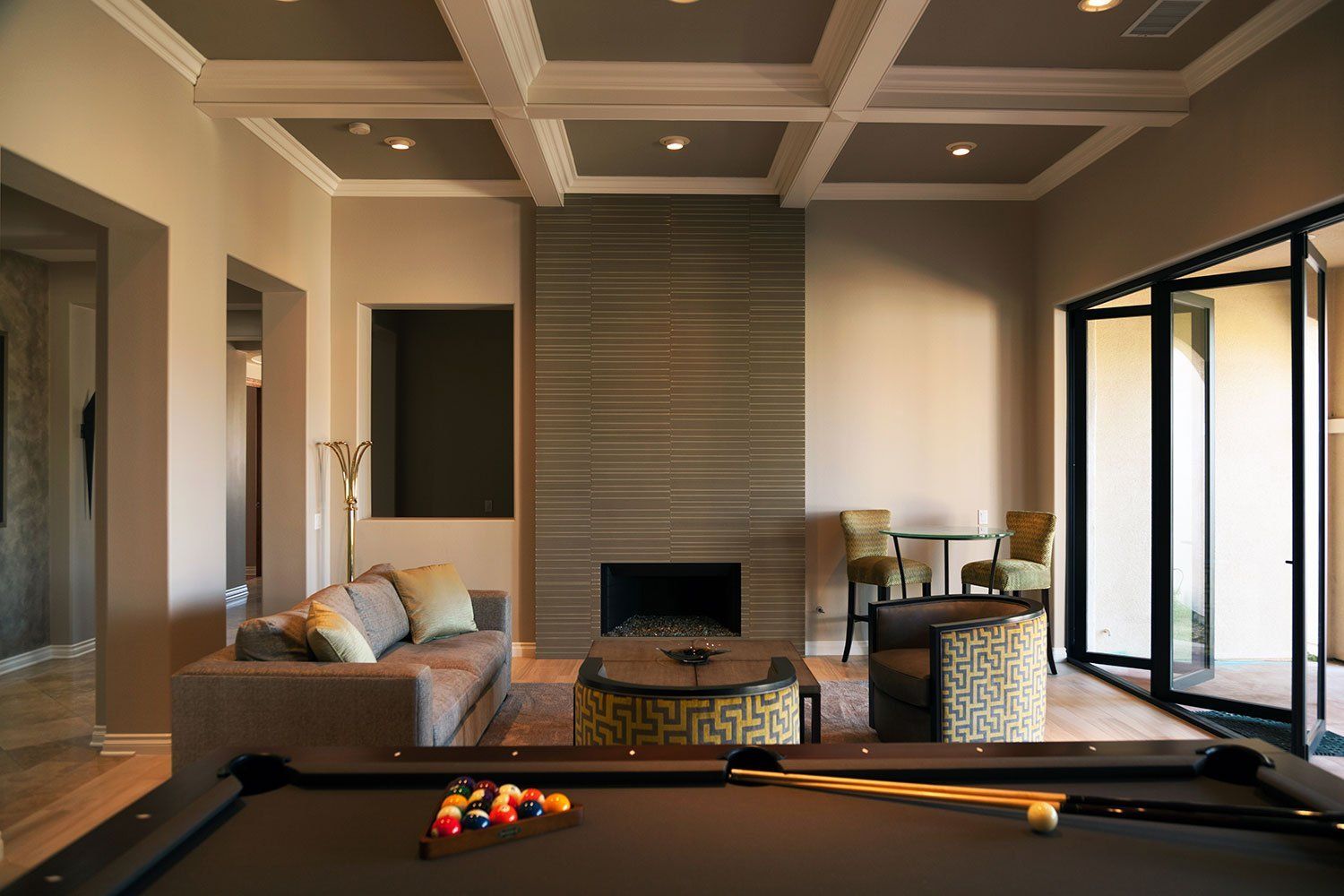 Modern living room with fireplace, sectional sofa, pool table, and floor-to-ceiling windows