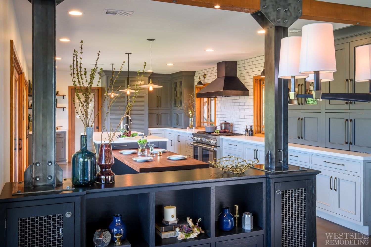 Modern kitchen and dining area with a large island, white cabinets, and dark wood beams