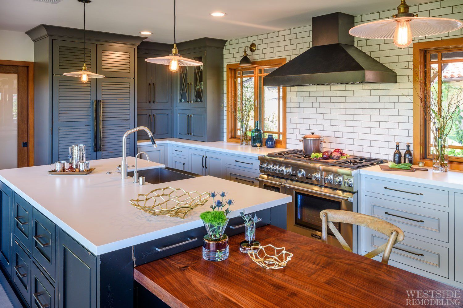 Modern kitchen with large island, pendant lights, white subway tile, and black range hood