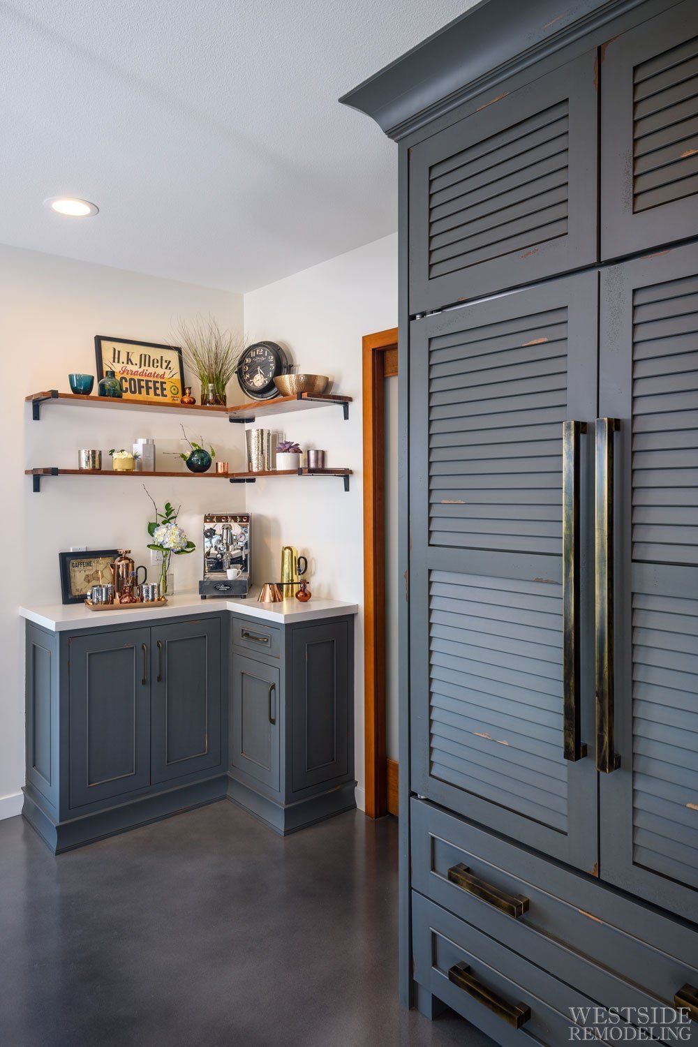 Gray built-in cabinets and shelves in a bright kitchen nook with decor and a doorway.
