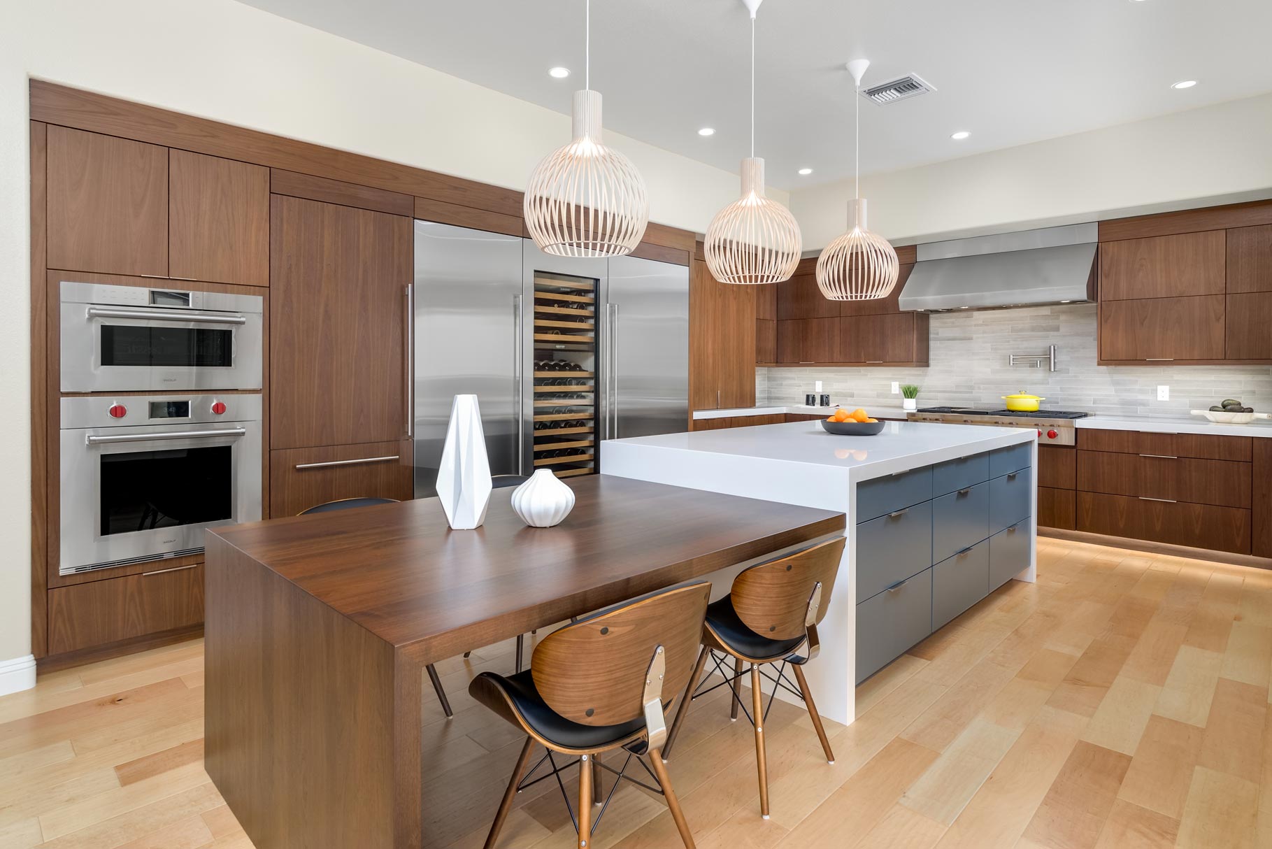 Modern kitchen with wood cabinets, large island, pendant lights, and small dining table