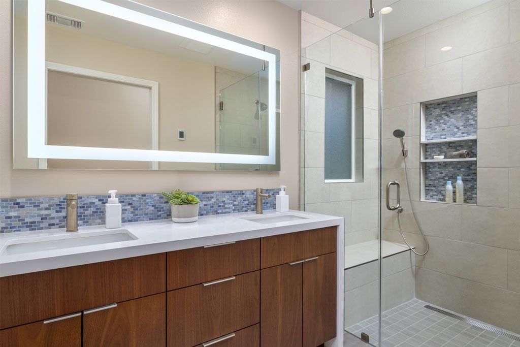 Accessible bathroom with double sink vanity, large mirror, and tiled shower area