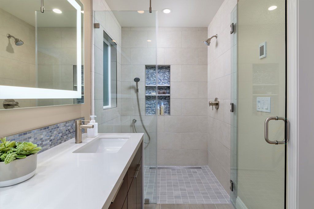 Modern bathroom with a walk-in shower, glass door, white vanity, and tiled walls