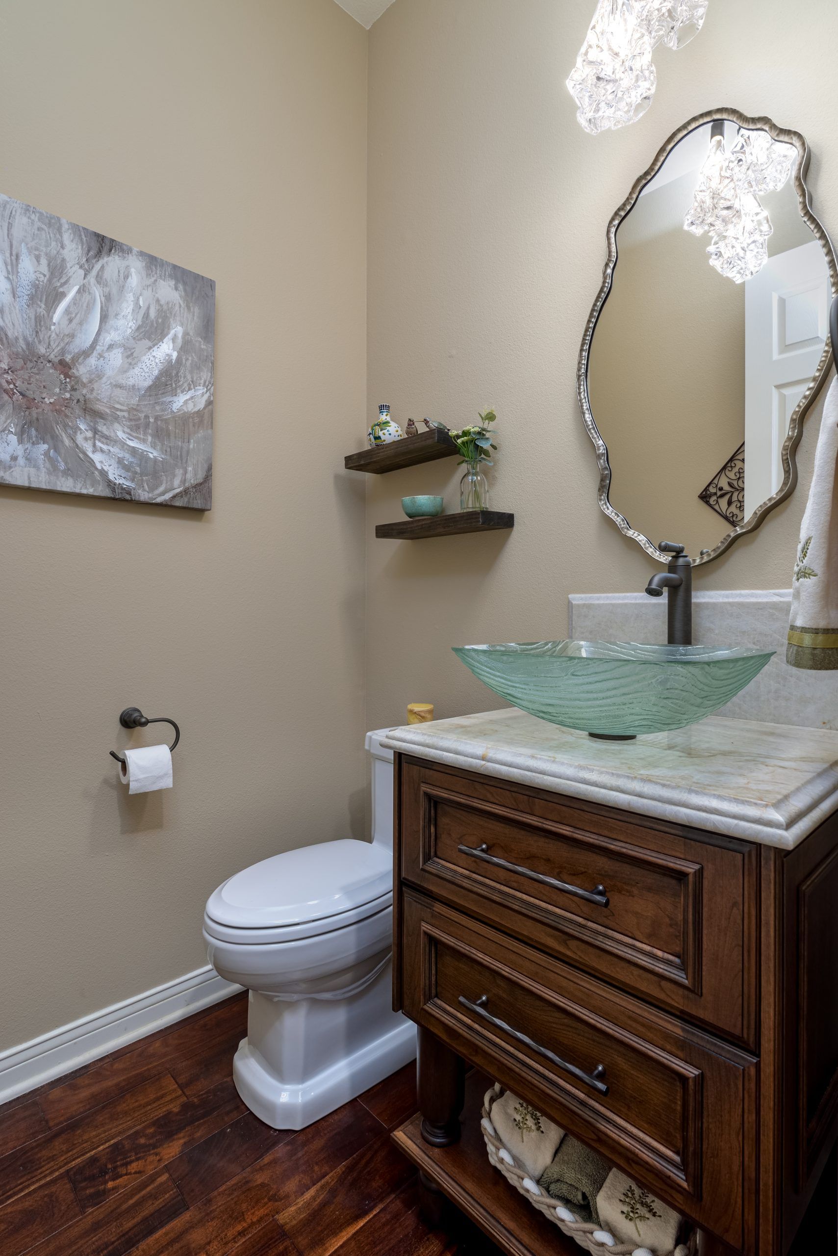 Small bathroom with vanity, green glass sink, ornate mirror, toilet, and wall decor