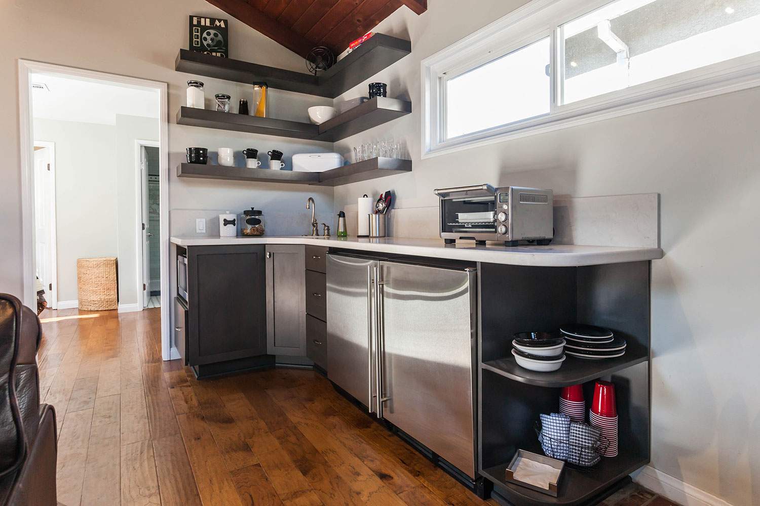 Modern kitchen with stainless steel appliances, floating shelves, and hardwood floors