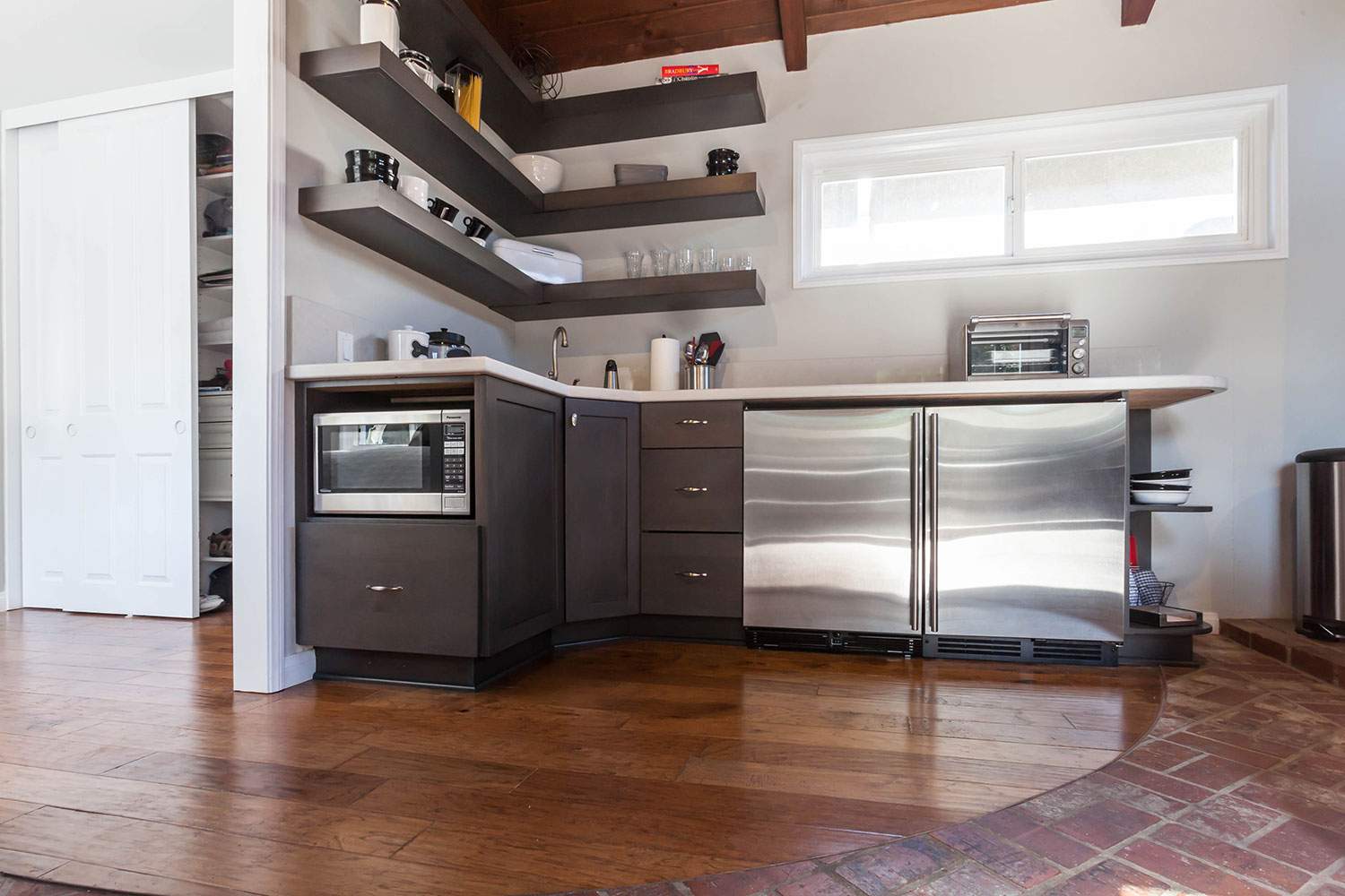 Modern kitchen with stainless-steel appliances, floating shelves, and hardwood floors