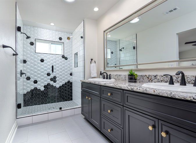 Modern bathroom with double vanity, large mirror, and black-and-white tiled walk-in shower