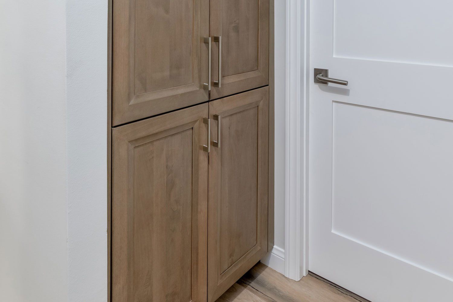 Built-in wood cabinet beside a white door in a hallway
