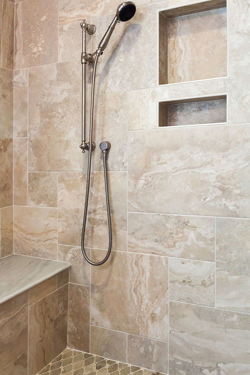Stone-tiled shower with handheld showerhead and built-in wall niches