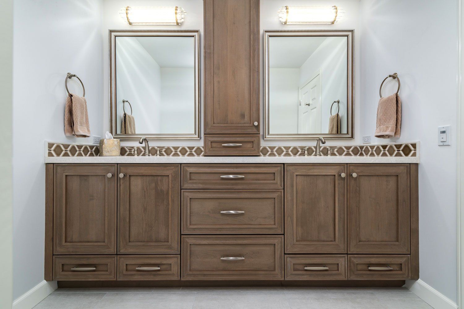 Double vanity bathroom with wood cabinets, two mirrors, and wall sconces