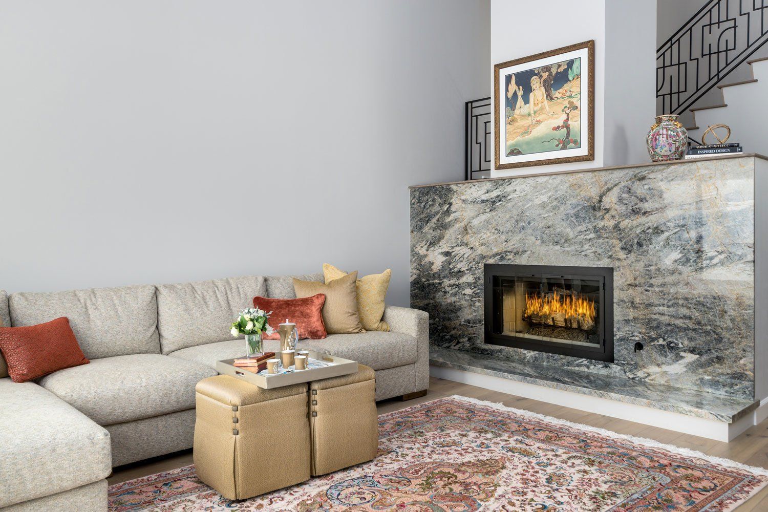 Cozy living room with sectional sofa, patterned rug, and lit stone fireplace with framed art above.